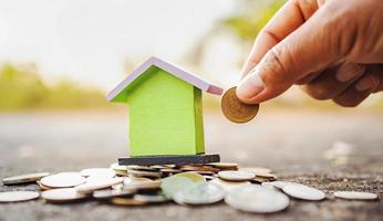 hand saving money with mini house and coins stack photo