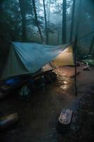 Wilderness Survival. Bushcraft Tent Under the Tarp in Heavy Rain, Embracing the Chill of Dawn. A Scene of Endurance and Resilience photo