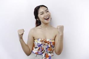 A young Asian woman with a happy successful expression wearing floral top isolated by white background photo