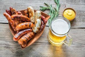 salchichas a la parrilla con un vaso de cerveza foto