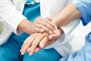 Doctor holding hands Asian elderly woman patient, help and care in hospital. photo