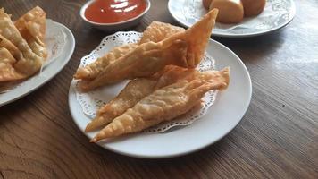 Pangsit, Pangsit Goreng, delicious Pangsit Ayam Goreng or Chicken Fried Dumpling, Indonesia Traditional Food made from flour and chicken, served on white sauce. photo