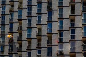 background of an apartment block with balconies and one yellow umbrella photo