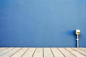 Blue Stucco Wall with Wooden Floor and Electrical Socket. photo