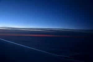 misterioso puesta de sol con nubes desde el avión ventana con foto