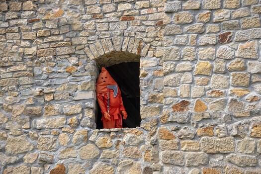 an executioner dressed in red standing in the window of a  castle photo