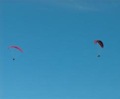 paragliders in the blue cloudless sky photo