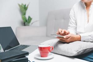 Social media day concept. Female freelancer starting working day early in living room for website with smartphone. Businesswoman working in home office. Woman communicating with online technology. photo