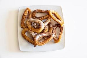 tasty, crunchy Spanish churros with sugar and cinnamon on a white plate photo