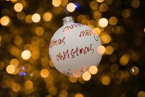 white bauble with red inscription merry christmas on a festive background photo