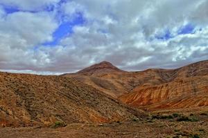 empty mysterious mountainous landscape from the center of the Canary Island Spanish Fuerteventura with a cloudy sky photo