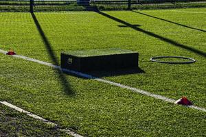 training football pitch with artificial green grass and training aids illuminated by the afternoon  sun photo