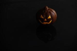 chocolate halloween pumpkin jack-o-lantern on dark background photo