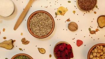 Healthy vegetarian food concept. Assortment of dried fruits, nuts and seeds on white background. Top view. video