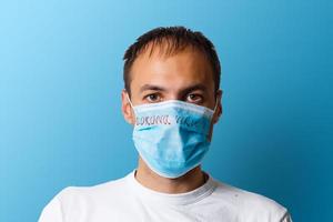 retrato de un enfermo hombre vistiendo médico máscara con coronavirus texto a azul antecedentes. coronavirus concepto. proteger tu salud. foto
