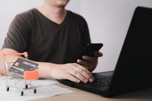 Men use laptop computers and smartphone for business commerce, which is payment online, sits on the chair in the living room at home on a laptop. The concept of finance and online shopping. photo