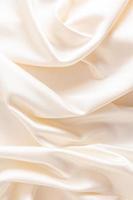 Delicate waves of satin fabric of beige color. vertical view. wedding background. photo