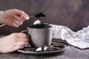 Children's hands take chocolate cake from a mug to eat photo