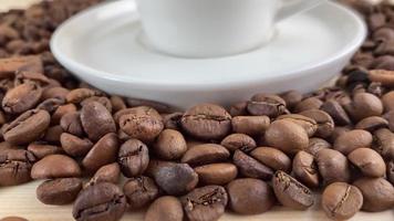 Coffee and a cup with a saucer. In the video, the camera moves smoothly, in the frame there are coffee beans and a white coffee cup with a saucer. video