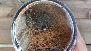 café frijoles son suelo en un café amoladora. en el video, café frijoles son suelo en un café amoladora con un transparente tapa, de cerca. video