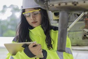 técnico arreglando el motor del avión, ingeniería aeroespacial femenina revisando los motores de los aviones, el mantenimiento mecánico asiático inspecciona el motor del avión foto