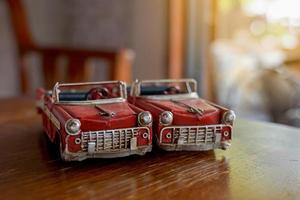 2 old red convertible car models placed side by side on a wooden table. Concept, collectibles, toys, decorations. Soft and selective focus. photo