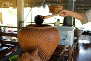 Use a dipper to draw water from a clay pot, which was the home drinking water point of villagers in the north or northeast of Thailand in the past. Soft and selective focus. photo