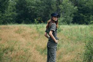 Woman in the woods in a gray jumpsuit blue cap back view photo