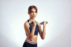 athletic slim woman workout with dumbbells fitness light background photo