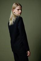 The blonde poses with her back to the camera. Concept photo for clothing brands. Cool offer for fashionable suits