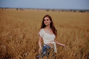 red-haired woman walking in the field nature summer lifestyle photo