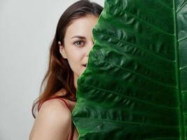 pretty woman with palm leaf half face light background photo
