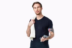 guy with a towel and dumbbells in his hand on a light background sports fitness bodybuilder photo