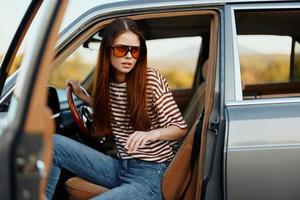 A woman driver in sunglasses stopped the car on the road in a pktkshestvie and is resting looking at a beautiful view photo