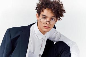 close-up portrait of handsome guy with curly hair wearing glasses and in a classic suit photo