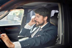 emocional hombre en un traje en un coche un viaje a trabajo comunicación por teléfono foto