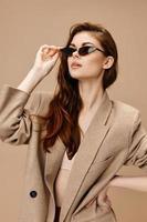 mujer en de moda lentes Mira a el lado en beige antecedentes y chaqueta Moda estilo foto