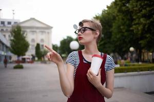 mujer con lentes en el calle hablando en el teléfono en un vaso con un bebida foto