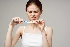 bonito mujer con un cepillo de dientes en mano Mañana higiene ligero antecedentes foto