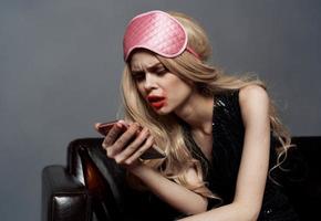 Drunk blonde woman with mobile phone makeup and pink sleep mask photo