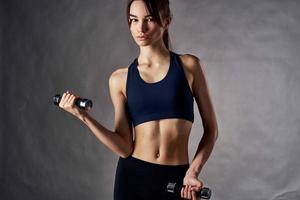 atlético mujer con un Delgado figura con pesas en el manos de aptitud rutina de ejercicio foto