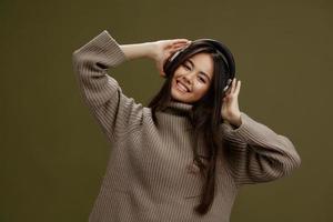 woman in a sweater listening to music with headphones fun Green background photo