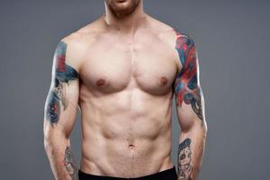 hombre con tatuajes en su brazos desnudo torso bombeo arriba abdominales rutina de ejercicio foto
