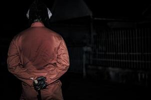 Asian handsome man wear clown mask with weapon at the night scene,Halloween festival concept,Horror scary photo of a killer in orange cloth