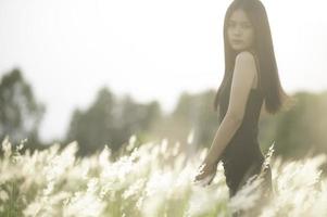 retrato de hermosa asiático mujer a césped campo en puesta de sol foto