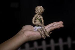 hand holding a rope doll on a black backgroun photo