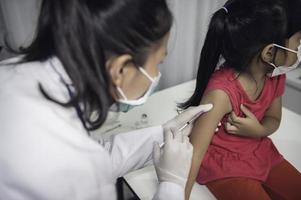 asiático médico inyección vacuna para proteger virus covid-19 a un niña vestir médico máscara, gente son muchachas son vacunado en contra influenza cada año. foto