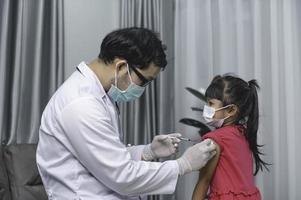 asiático médico inyección vacuna para proteger virus covid-19 a un niña vestir médico máscara, gente son muchachas son vacunado en contra influenza cada año. foto