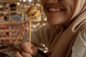 el niña sonrisa cuando comiendo el tradicional bocadillo tahu walik foto