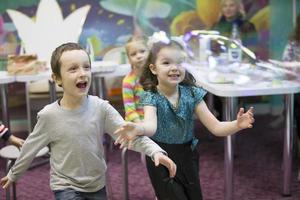 Belarus, Gomel, November 9, 2017. Gomel Children's Center.Children at the feast. Soap bubbles show. Children's party. To burst the soap bubble photo